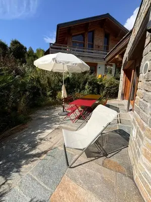 two chairs and an umbrella in front of a house at Superbe chalet vallée de Chamonix in Chamonix-Mont-Blanc