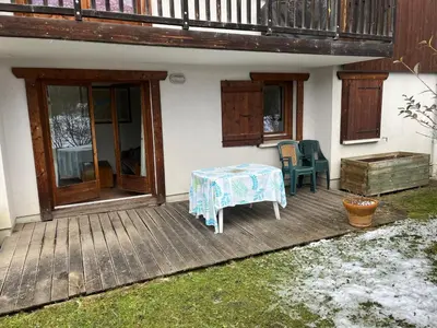 a wooden deck with a table and chairs on it at Appartement Samoëns in Samoëns