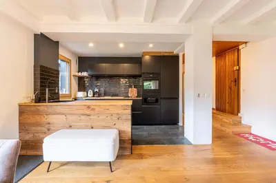 a kitchen with a wooden counter and a white stool at Appartement des Cristaux - Welkeys in Megève