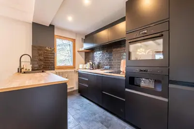 a kitchen with black cabinets and a sink and an oven at Appartement des Cristaux - Welkeys in Megève