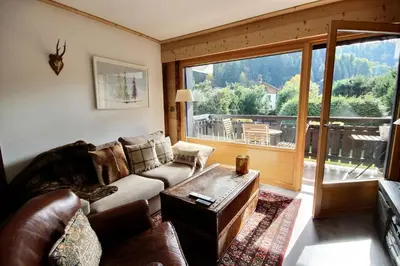 a living room with a couch and a large window at Cosy apartment with fireplace close to the slopes in Megève