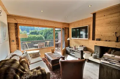 a living room with a couch and a large window at Cosy apartment with fireplace close to the slopes in Megève