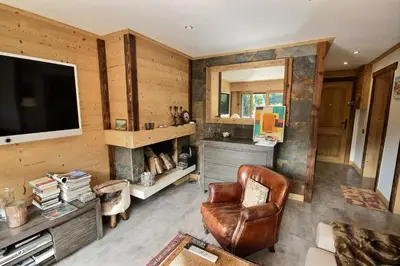 a living room with a television and a leather chair at Cosy apartment with fireplace close to the slopes in Megève