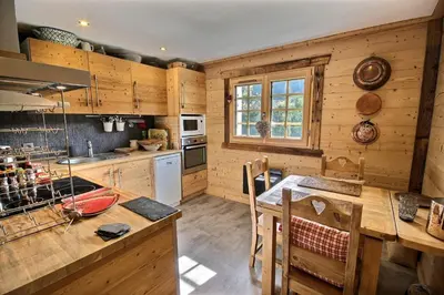 a kitchen with wooden cabinets and a wooden table at Cosy apartment with fireplace close to the slopes in Megève