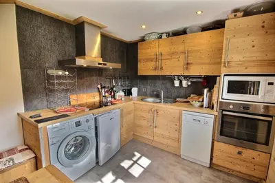 a kitchen with wooden cabinets and a washer and dryer at Cosy apartment with fireplace close to the slopes in Megève