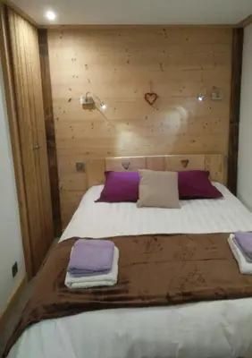 a bedroom with a large bed with wooden walls at Cosy apartment with fireplace close to the slopes in Megève