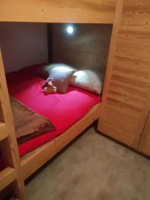 a wooden bunk bed with a teddy bear laying on it at Cosy apartment with fireplace close to the slopes in Megève