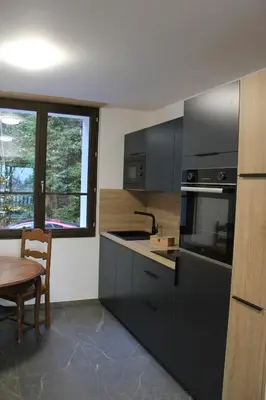 a kitchen with black cabinets and a table and a window at Le Manoir d Ernesta in Passy