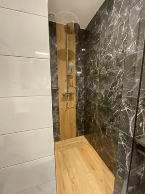 a bathroom with a shower with black marble walls at Le Manoir d Ernesta in Passy