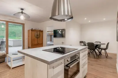 a kitchen with a stove top oven next to a living room at Le 002 - Proche Telecabine - Terrasse in Saint-Gervais-les-Bains