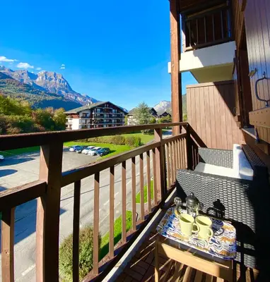 a balcony with a table with a tea set on it at Le coin cosy des 4 têtes - balcon - vue montagnes - proche centre & gare in Sallanches