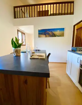 a kitchen with a island with a black counter top at Le coin cosy des 4 têtes - balcon - vue montagnes - proche centre & gare in Sallanches