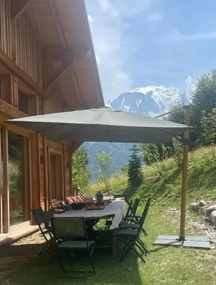 a table and chairs under an umbrella on a patio at Chalet prestige Saint Gervais les Bains in Saint-Gervais-les-Bains