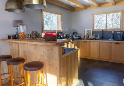 a kitchen with wooden cabinets and a counter with stools at Chalet prestige Saint Gervais les Bains in Saint-Gervais-les-Bains