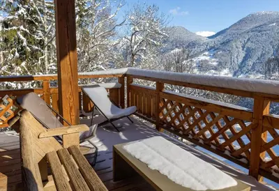 a deck with a bench and a chair and mountains at Chalet prestige Saint Gervais les Bains in Saint-Gervais-les-Bains