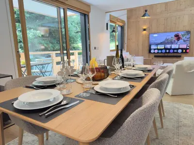 a wooden table with chairs and plates and wine glasses at Les cimes de l alpage - Duplex luxe 130 m2 au pied des pistes in Combloux