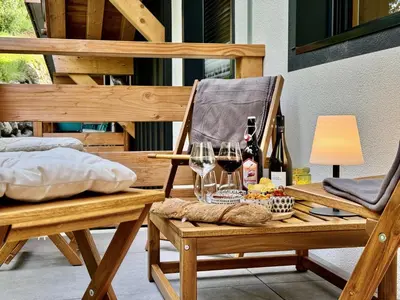 a wooden chair with a table with wine glasses at Les cimes de l alpage - Duplex luxe 130 m2 au pied des pistes in Combloux