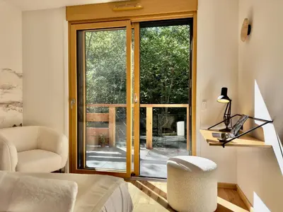 a living room with a sliding glass door and a chair at Les cimes de l alpage - Duplex luxe 130 m2 au pied des pistes in Combloux