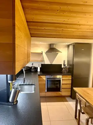 a kitchen with a stainless steel refrigerator and wooden ceilings at Marmotte Mountain Pic Vert in Chamonix-Mont-Blanc