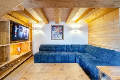 a living room with a blue couch and a tv at Marmotte Mountain Pic Vert in Chamonix-Mont-Blanc