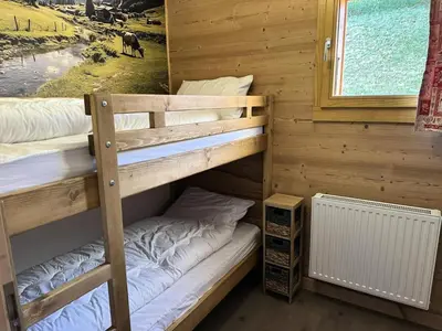 two bunk beds in a cabin with a window at Chalet Flore - CHALET FLORE MAE-6641 in Combloux