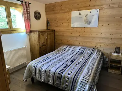 a bedroom with a bed in a wooden wall at Chalet Flore - CHALET FLORE MAE-6641 in Combloux