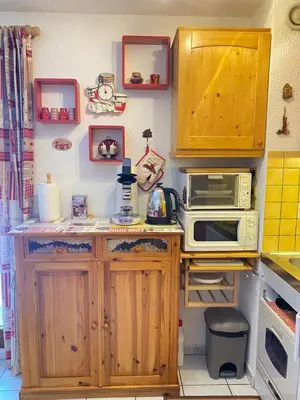 a small kitchen with wooden cabinets and a microwave at Studio in Arâches-la-Frasse