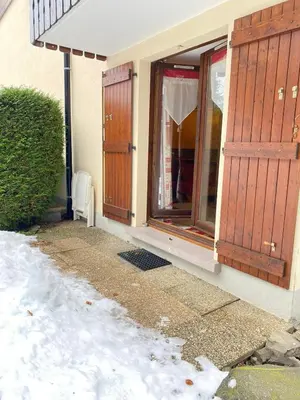 a house with wooden doors and snow on the ground at Studio in Arâches-la-Frasse