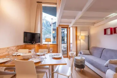 a living room with a table and a blue couch at Ancolie - Apartment Free parking close to ski lift - By Cozee Rentals in Chamonix-Mont-Blanc