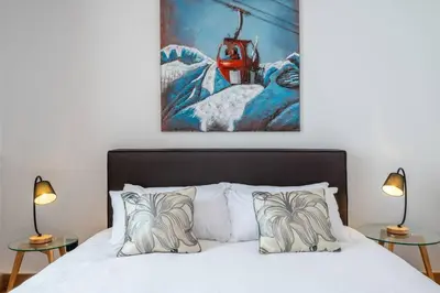 a bedroom with a bed with two lamps and a painting at Le Freney - New Apartment in Town Center & Free parking - By Cozee Rentals in Les Houches