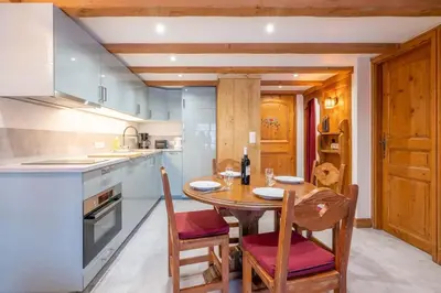 a kitchen with a wooden table and chairs in a kitchen at Le Cristal - Central apartment close to the slopes & Free Parking - By Cozee Rentals in Chamonix-Mont-Blanc