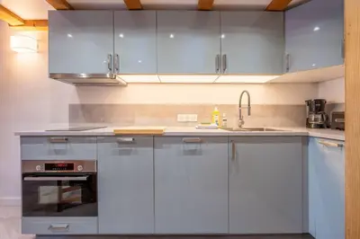 a kitchen with white cabinets and a sink at Le Cristal - Central apartment close to the slopes & Free Parking - By Cozee Rentals in Chamonix-Mont-Blanc