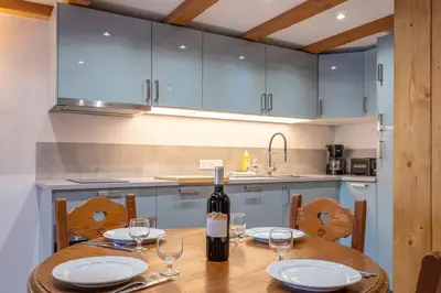 a kitchen with a wooden table with a bottle of wine at Le Cristal - Central apartment close to the slopes & Free Parking - By Cozee Rentals in Chamonix-Mont-Blanc