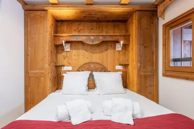 a bedroom with a bed with a wooden wall at Le Cristal - Central apartment close to the slopes & Free Parking - By Cozee Rentals in Chamonix-Mont-Blanc