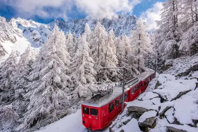 a red train traveling through the snow covered mountains at Clos Savoy - New Apartment Close to City center & Free parking - By Cozee Rentals in Chamonix-Mont-Blanc