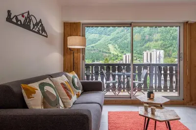 a living room with a couch and a large window at Clos Savoy - New Apartment Close to City center & Free parking - By Cozee Rentals in Chamonix-Mont-Blanc