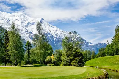 a golf course with a snow covered mountain in the background at Prarion - Modern apartment Next to Ski lift - By Cozee Rentals in Les Houches