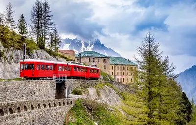 a red train on a bridge over a mountain at Prarion - Modern apartment Next to Ski lift - By Cozee Rentals in Les Houches