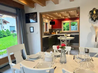 a dining room with a table and chairs and a kitchen at La Maison Magique! Magnifique chalet familial in Sallanches