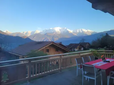 a table and chairs on a balcony with mountains at La Maison Magique! Magnifique chalet familial in Sallanches