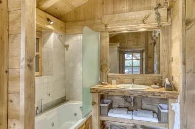 a bathroom with a tub and a sink and a mirror at Chalet Altitude in Megève