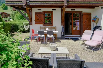 a patio with chairs and a table in front of a house at Ali'Home vue MontBlanc - T2 de charme in Demi-Quartier