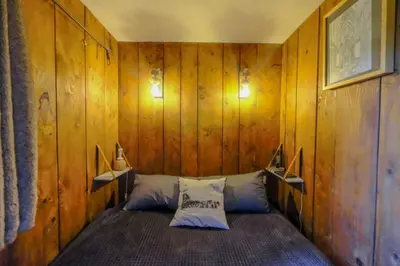 a room with a bed in a wooden wall at Ali'Home vue MontBlanc - T2 de charme in Demi-Quartier