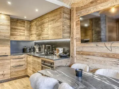 a kitchen with wooden walls and a table with chairs at Appartement rénové 2 pièces, balcon, parking à Megève - FR-1-453-319 in Megève