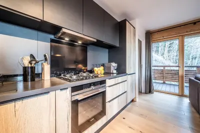 a kitchen with black cabinets and a stove top oven at Maira Les Carroz - by EMERALD STAY in Arâches-la-Frasse