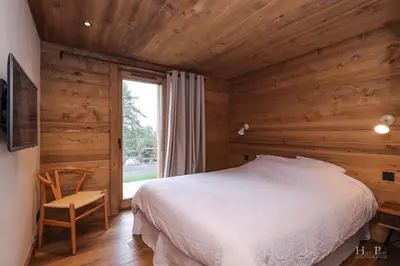 a bedroom with wooden walls and a bed and a window at Chalet du Gouter in Combloux