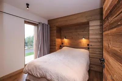 a bedroom with wooden walls and a bed with a window at Chalet du Gouter in Combloux