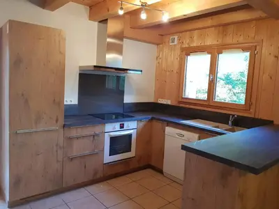a kitchen with wooden cabinets and a stove top oven at Chalet la Cry à St Gervais in Saint-Gervais-les-Bains