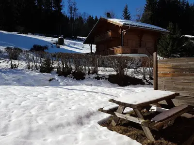a picnic table in the snow next to a cabin at Chalet la Cry à St Gervais in Saint-Gervais-les-Bains