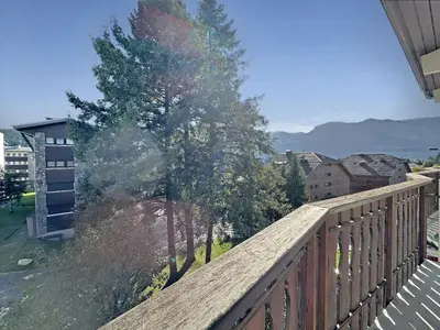 a balcony with a wooden railing and a tree at CL339 - Appartement 6 personnes centre village in Les Carroz d'Araches